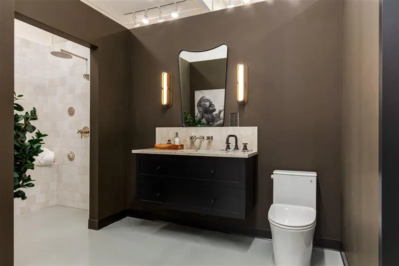 Showroom bathroom vignette with a black vanity, arched mirror and brass fixtures