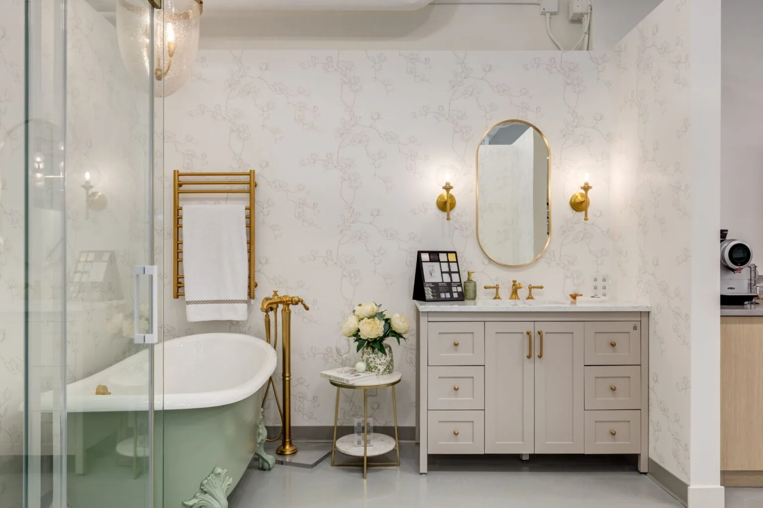 Showroom bathroom vignette with a freestanding tub, patterned wallpaper and brass fixtures