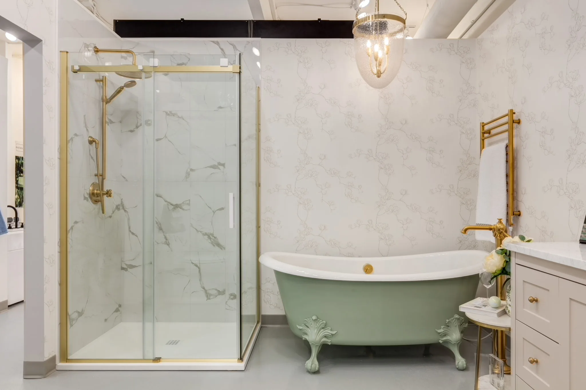 Showroom display with a marble glass shower and a green clawfoot tub with brass fixtures