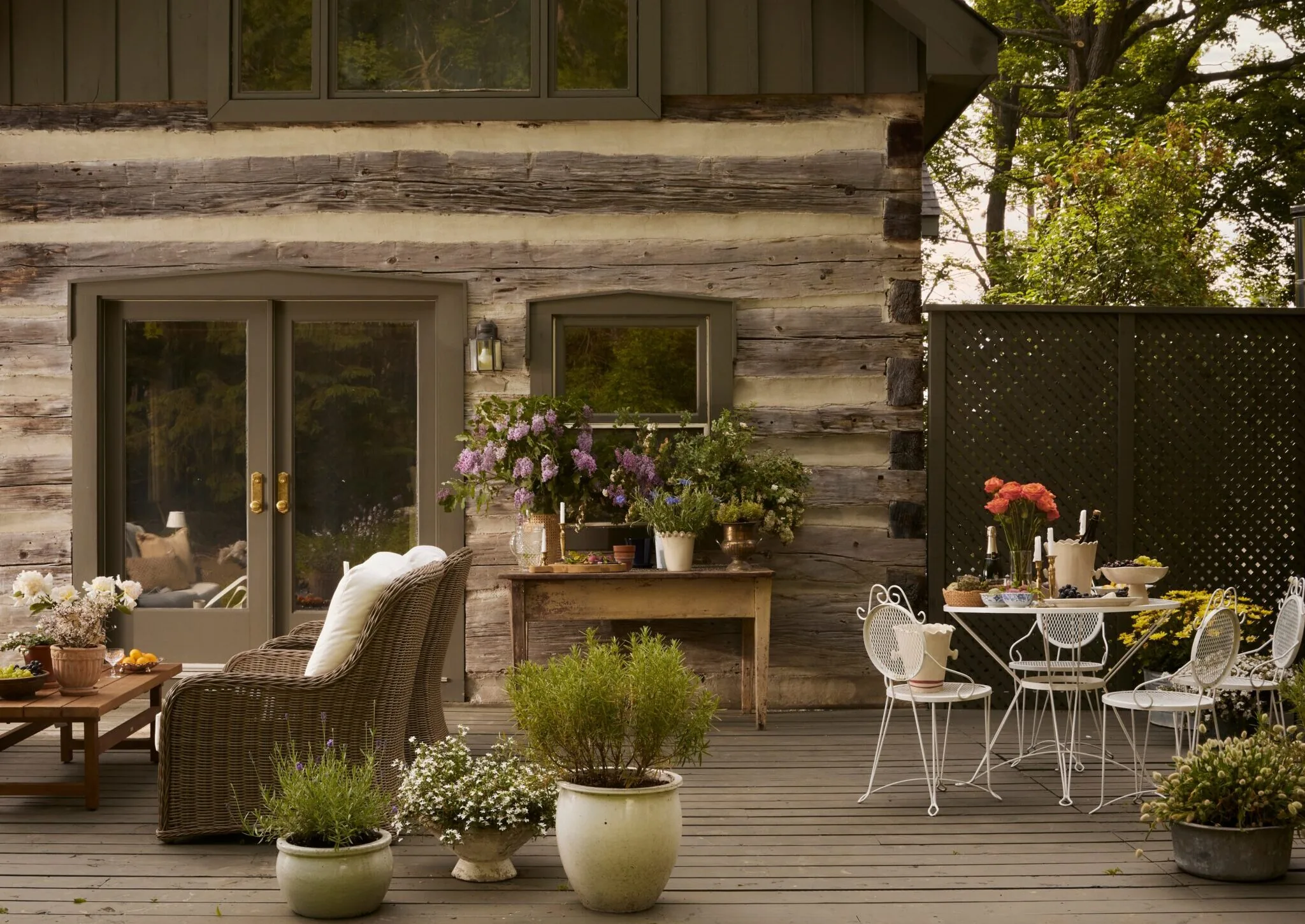 Rustic log home covered patio with outdoor seating and potted plants