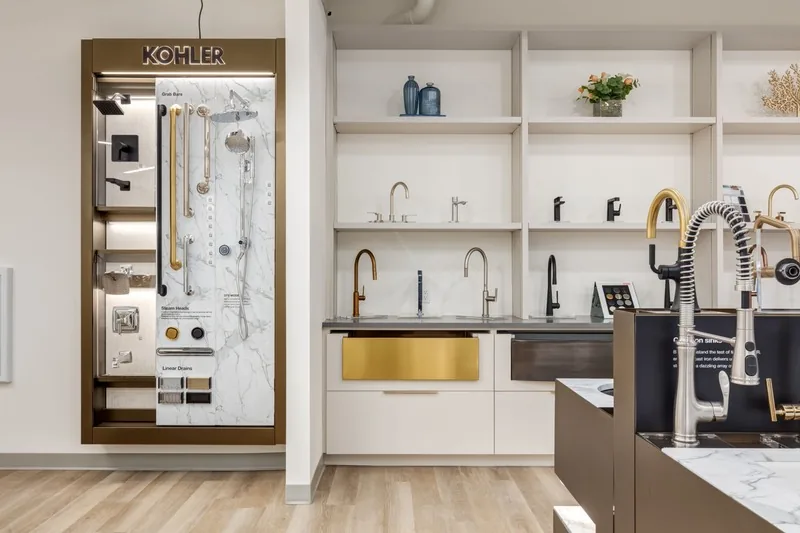 Kohler fixture display wall with faucets and a gold undermount sink in the Baths by Design showroom