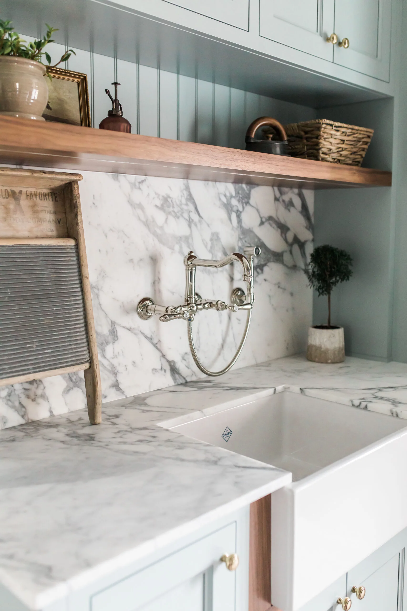 Marble apron-front sink with a wall-mounted bridge faucet and green shelving in Carolyn Wilbrink's project